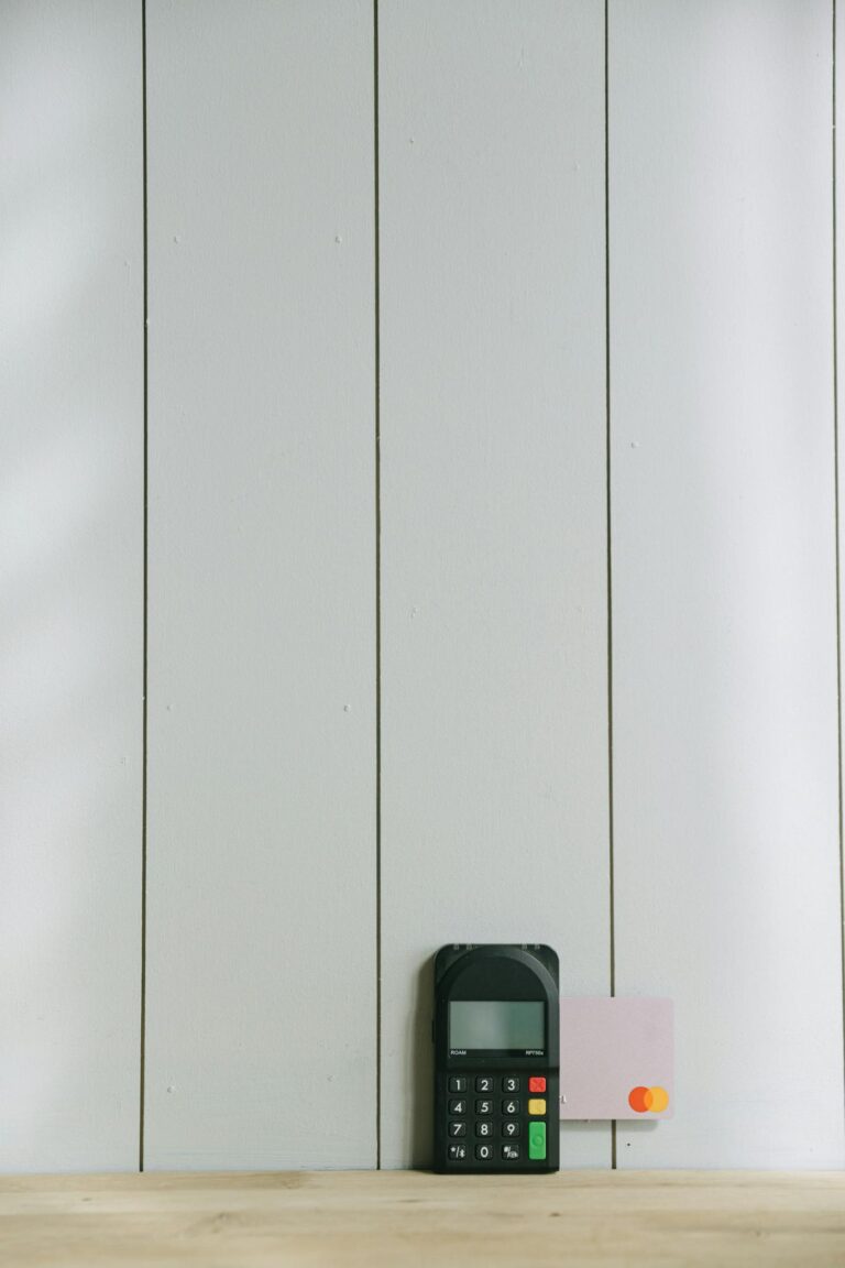 A sleek payment terminal with buttons against a white wooden background, ideal for finance concept.